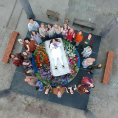 Dido's body on a bier, dressed in white, surrounded by a circle of mourners
